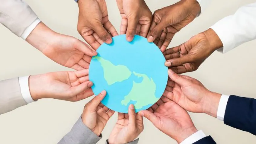 hands of different colors create a circle and hold an image of the Earth