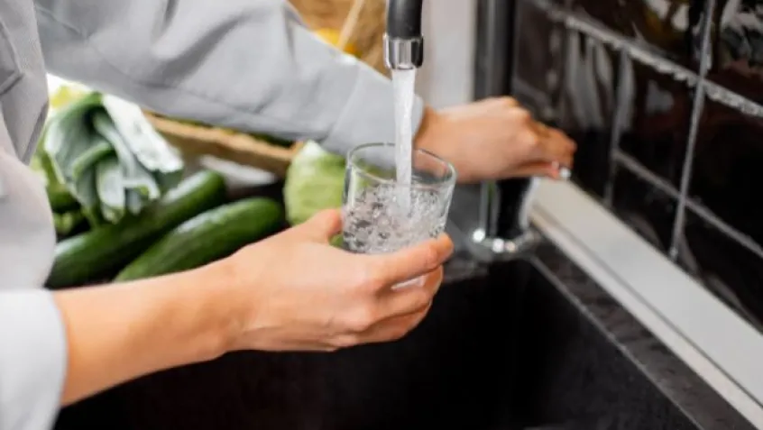 a person fills a glass of water from the kitchen sink tap