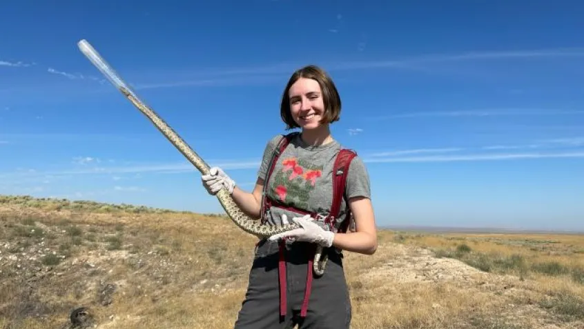 Student Abella Cathey, holds a snake while during a STEM conservation field project.