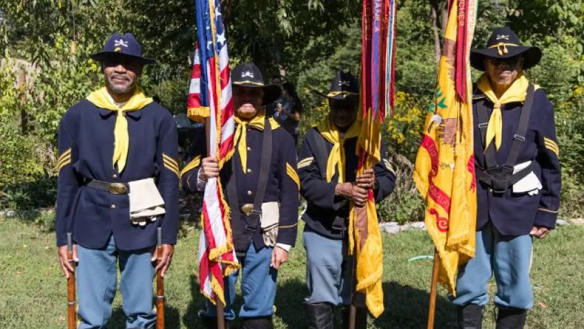 four men in buffalo soldier uniform hold flags as they pose during National Public Lands