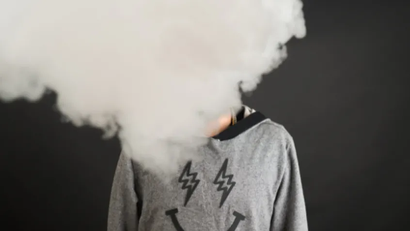A person's face is covered by a cloud of smoke