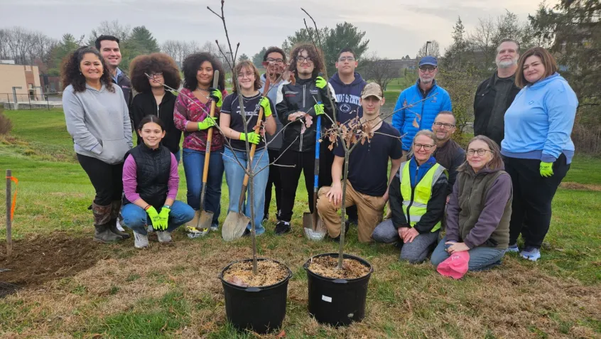 students from McCaskey high school stand near two trees ready for planting