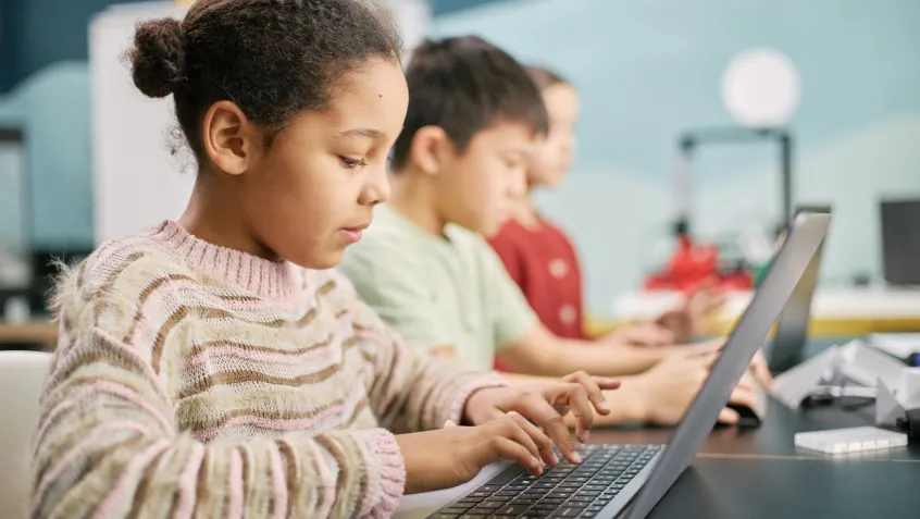 a young girl uses a computer in a classroom