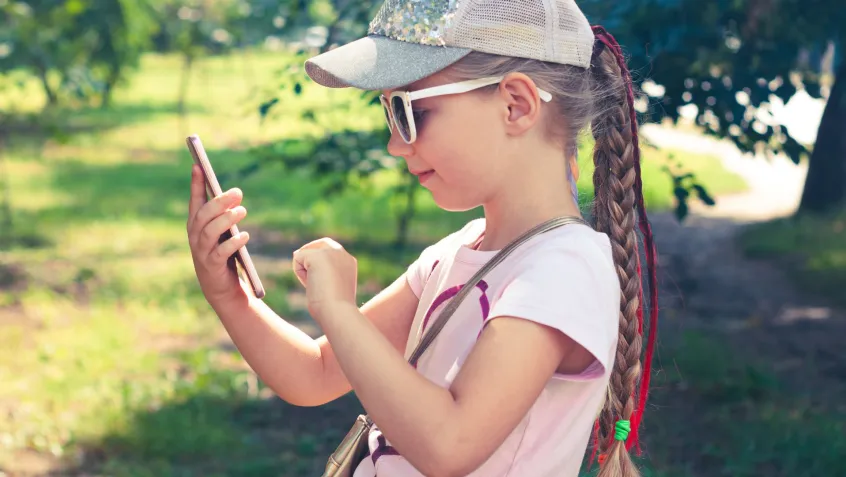 a young girl uses a cellphone outside