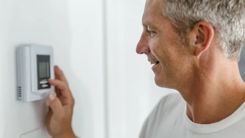Smiling daddy adjusting the thermostat