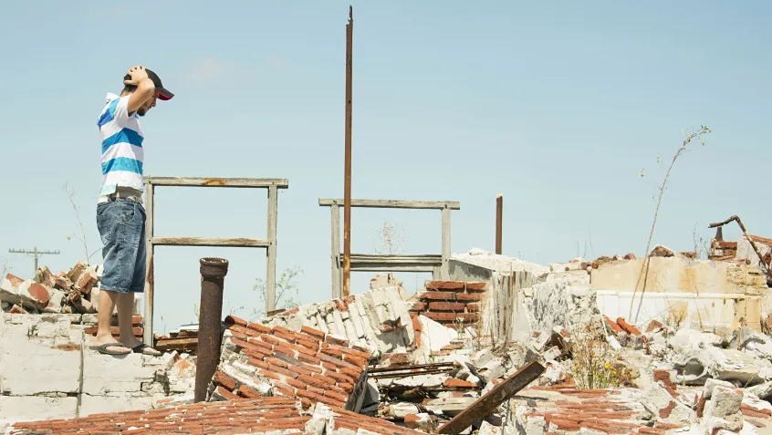 Man surveying destruction from a natural disaster