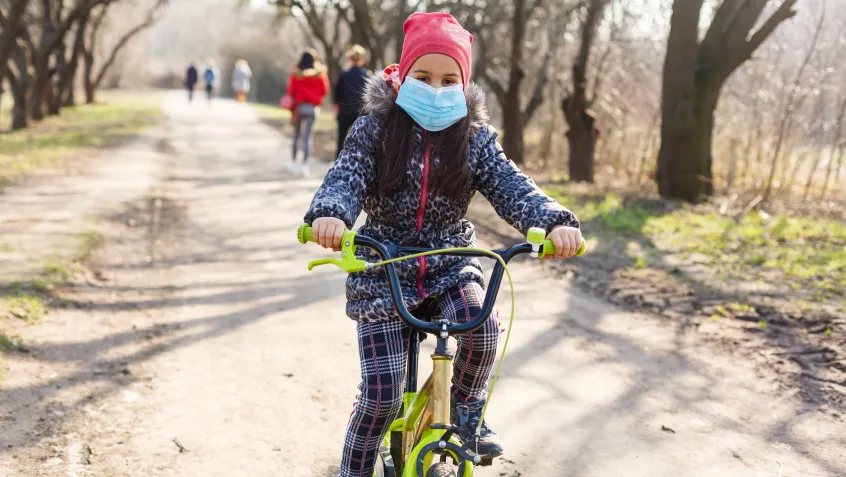 Girl with a mask on riding a bike