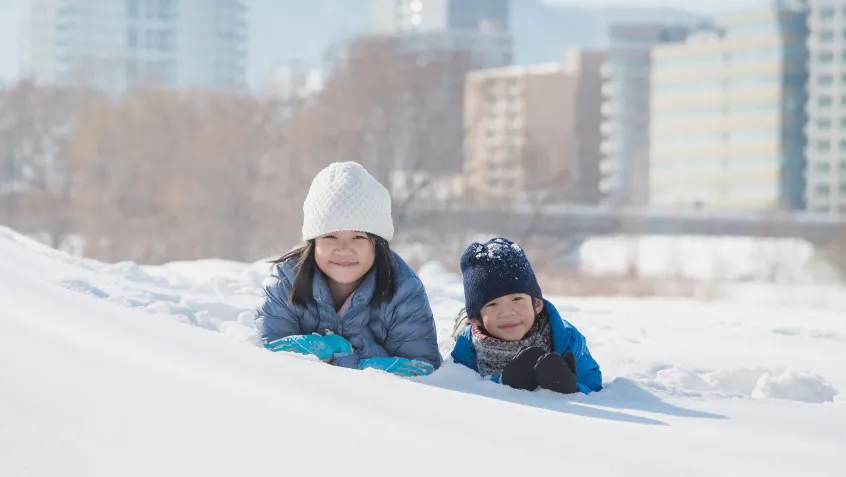 Brother and sister playing in the snow outside