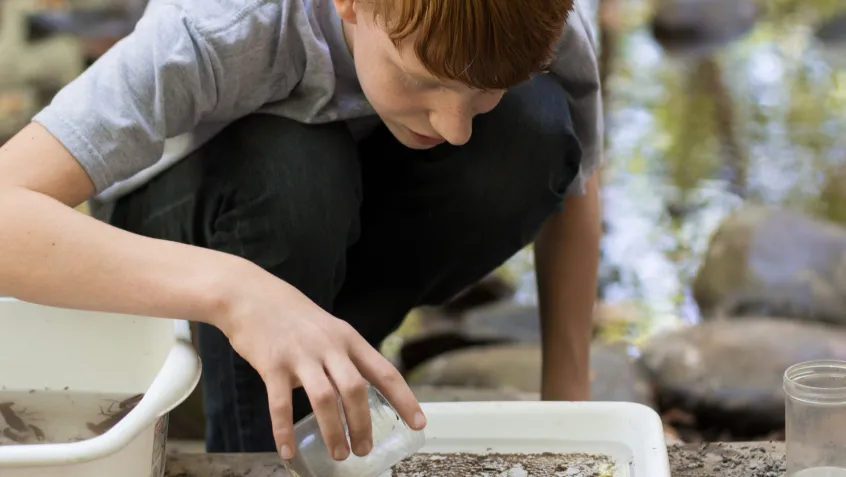 Young student looking at water sample during environmental education activity