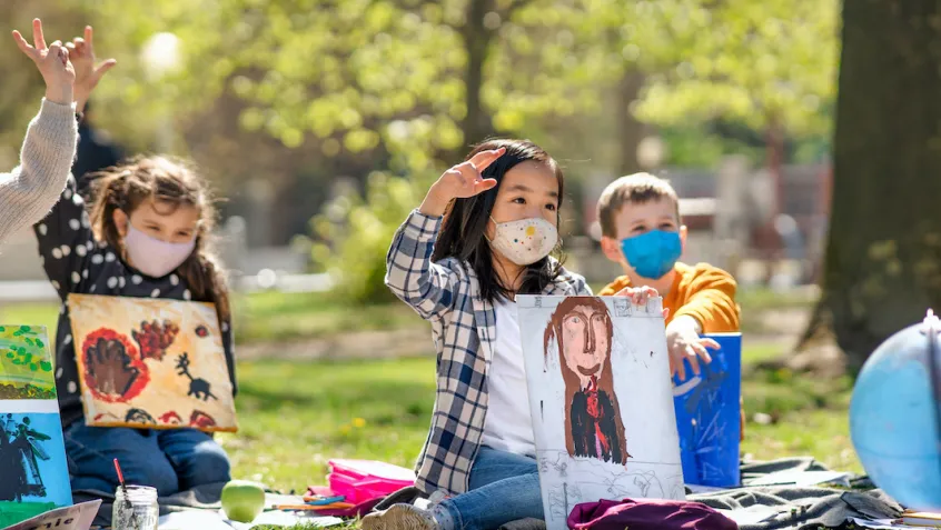 young students wearing masks in a park for an outdoor school lesson