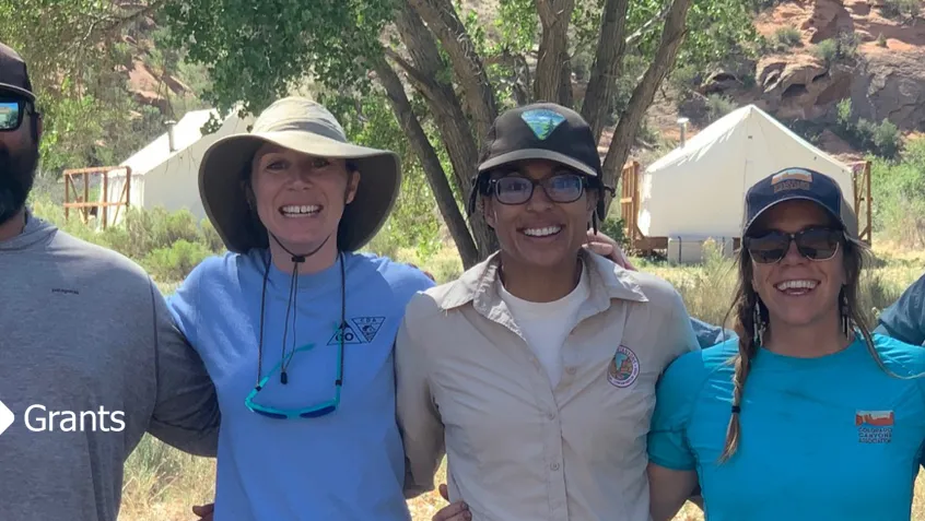 Photo of Bureau of Land Management and nonprofit partners arm in arm smiling.