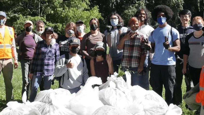 photo of group standing in front of pile of trash bags after a clean-up.