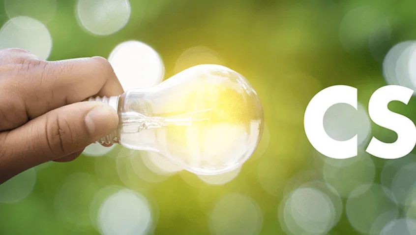 Photo of young hand holding a lightbulb with the letters CSR to the right and green in background