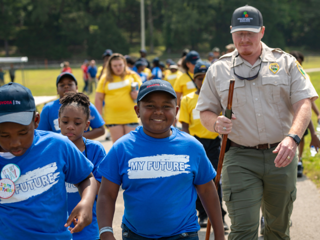 Young boy walking with NPS ranger and group outdoors