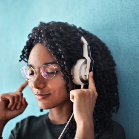 a young woman closes her eyes while listening to head phones