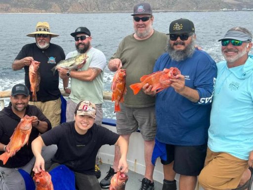 a group of veterans standing in a boat hold up fish they caught