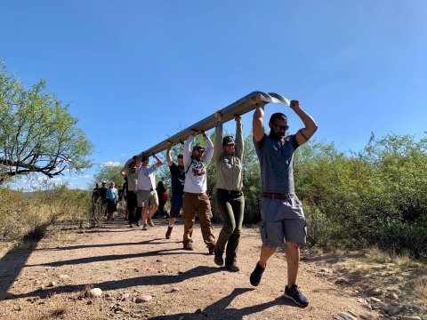 a group of volunteers carry a large guardrail in the outdoors