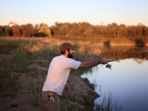 a man uses a fishing pole on a lake