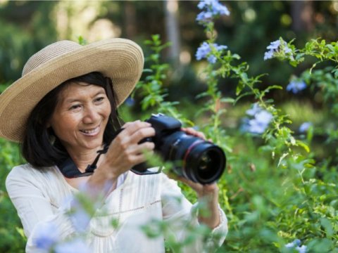 a woman holds a camera taking a photo of flowers