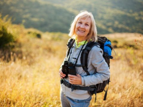 a woman with binoculars hiking on a trail