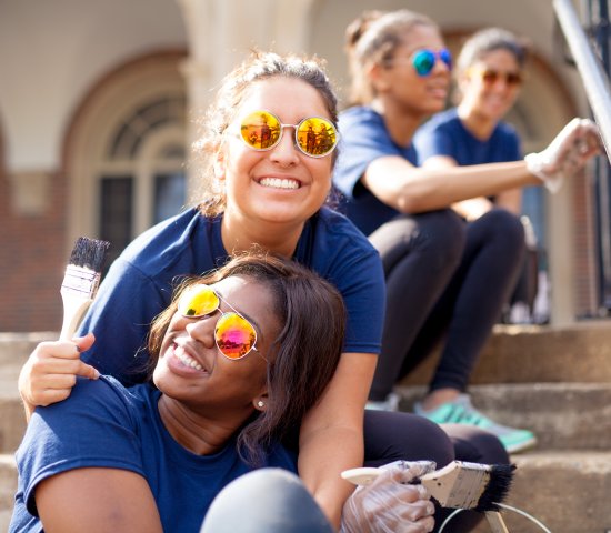 Two young women on stairs painting and smiling