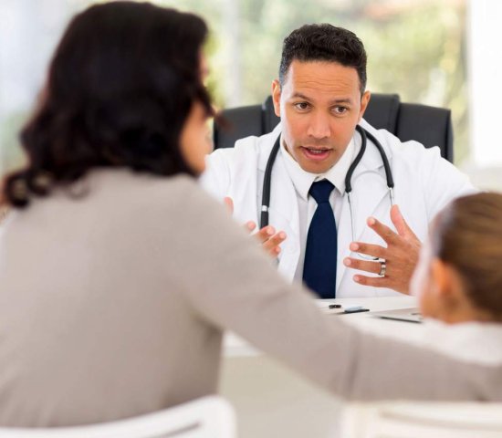 Doctor talking to mother and child across a desk