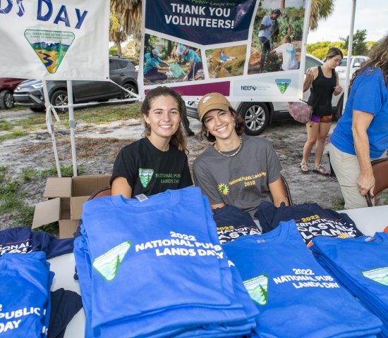 Smiling young people behind a table of shirts