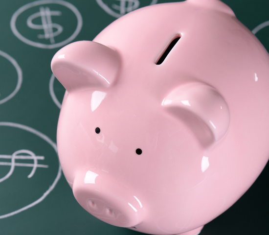 Pink piggy bank on green floor with dollar signs