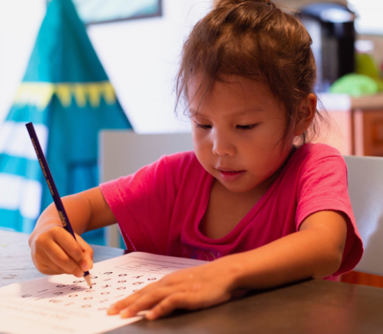 Young girl doing word find puzzle at a table indoors