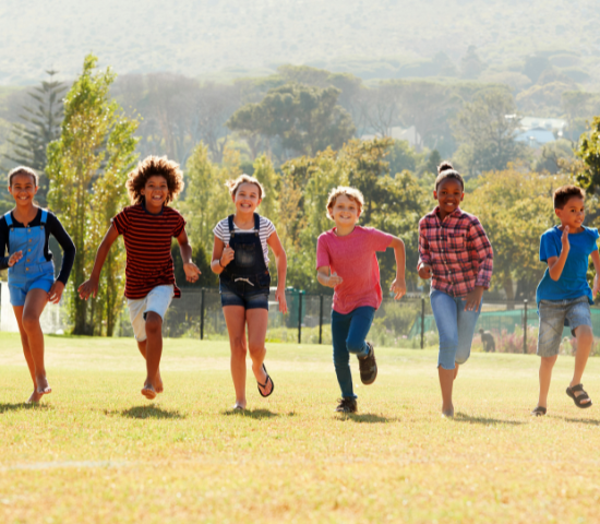 Kids running outdoors in a line towards the camera smiling