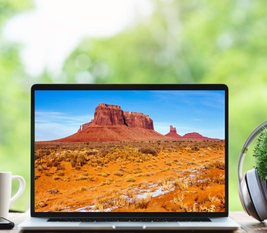 a laptop computer sits on a table with an image of southwestern mountains on a screen for national public lands day virtual event
