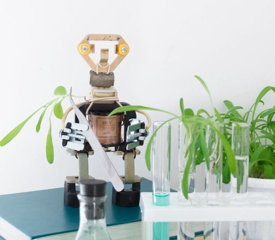 a robot stands next to test tubes filled with plants