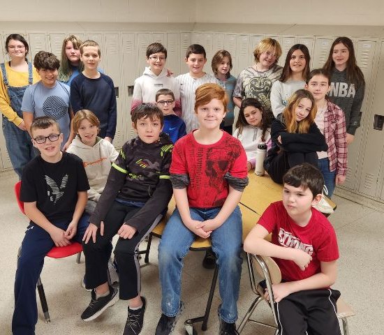 students sitting on a table and standing in a group smiling