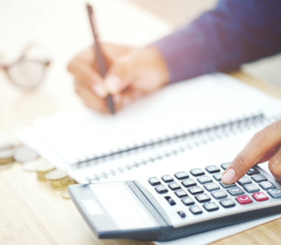 Person with pen and paper using a calculator