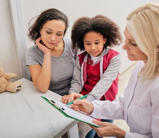 a female doctor fill out a form with a mother and daughter