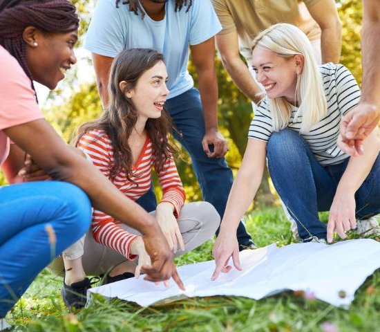 a group of people outside pointing to a large paper making a plan