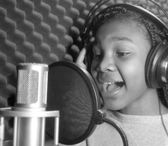 Heaven White, a young girl singing into a microphone with headphones on