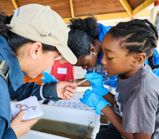 Woman in hat helping young girl with water samples