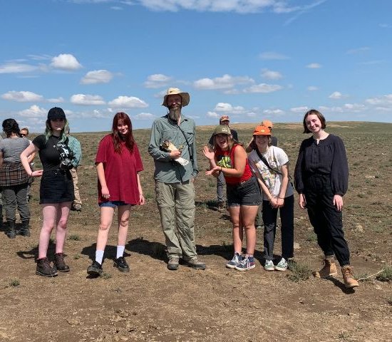 a Bureau of Land Management Biologist holds a raptor with a group of students during a Greening STEM Project