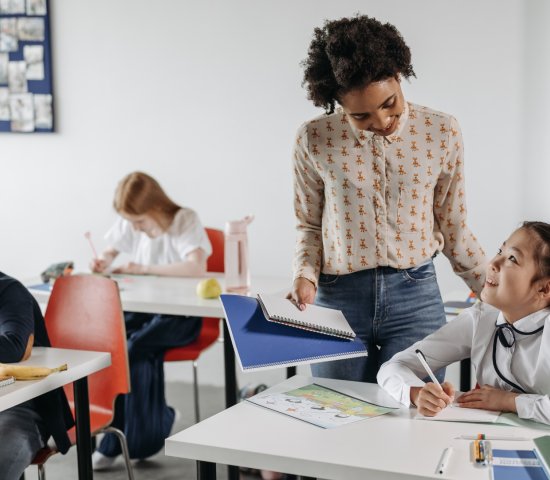 a teacher speaks to a student at her desk