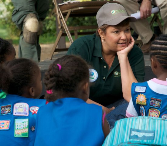 An educator speaks with a group of girl scouts at a volunteer event