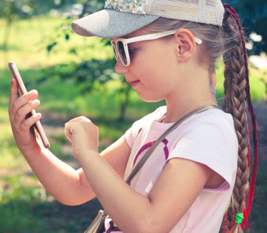 a young girl uses a cellphone outside