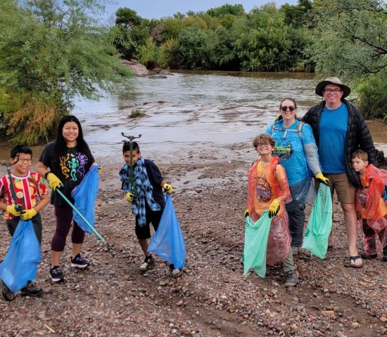 families volunteer on National Public Lands Day collecting trash on a riverbank