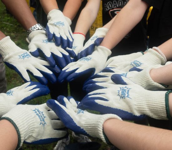 a group of volunteers put their hands together in a circle before an activity 