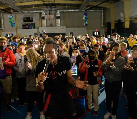 AY Young performing in front of group of students in gymnasium