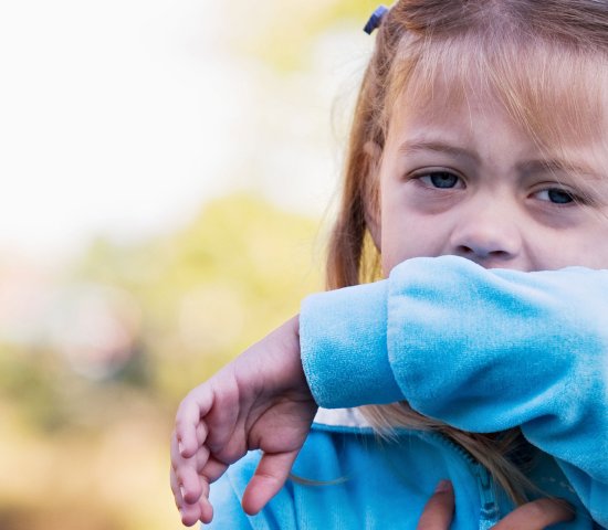 Girl coughing into her elbow