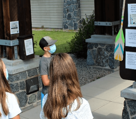 Forest Service staff pointing to announcement board instructing group of middle school students.