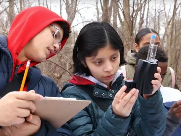 Photo of two students using water tester equipment for STEM project outside