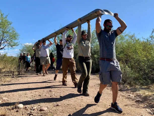 volunteers carry a large guardrail over their heads during a National Public Lands Day event