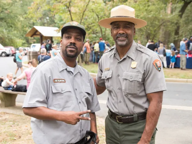 two men in national park ranger uniforms smile during national public lands day event